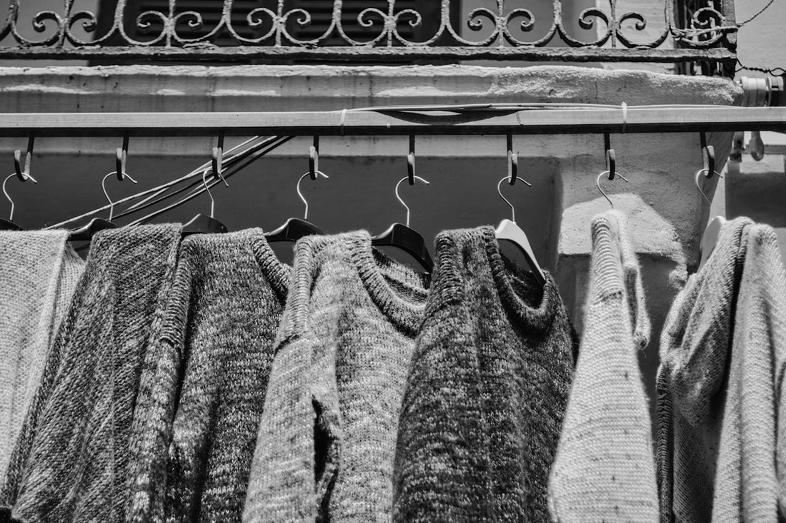 A black and white photo of clothes hanging on a rack