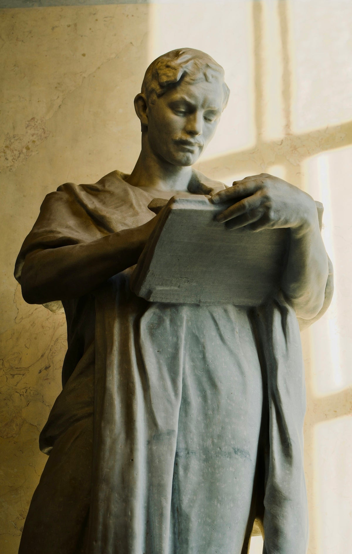 Statue of a man reading a book.