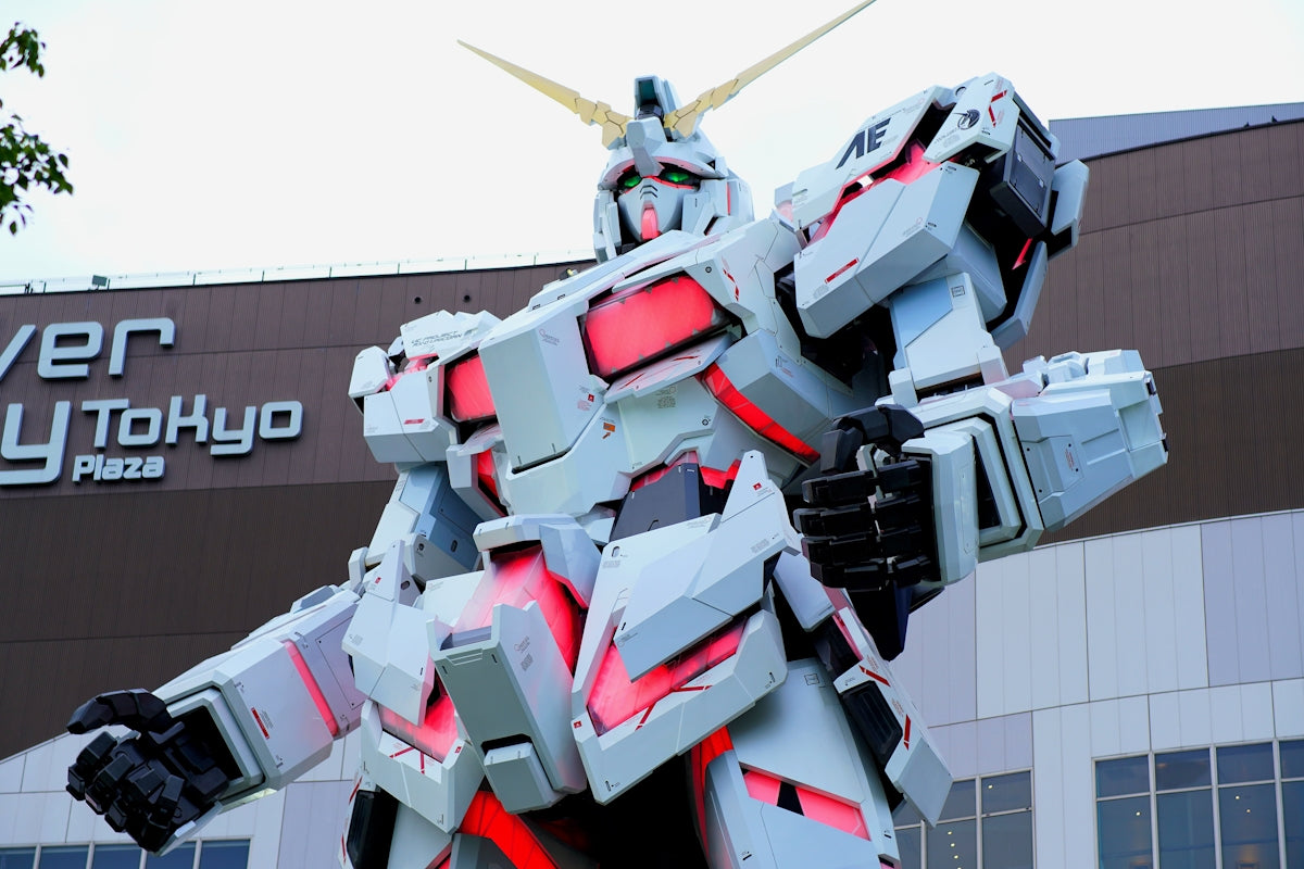 A giant gundam statue stands in front of a building.