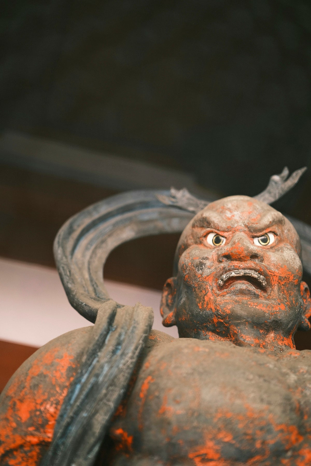 Ancient statue with fierce expression and red markings.