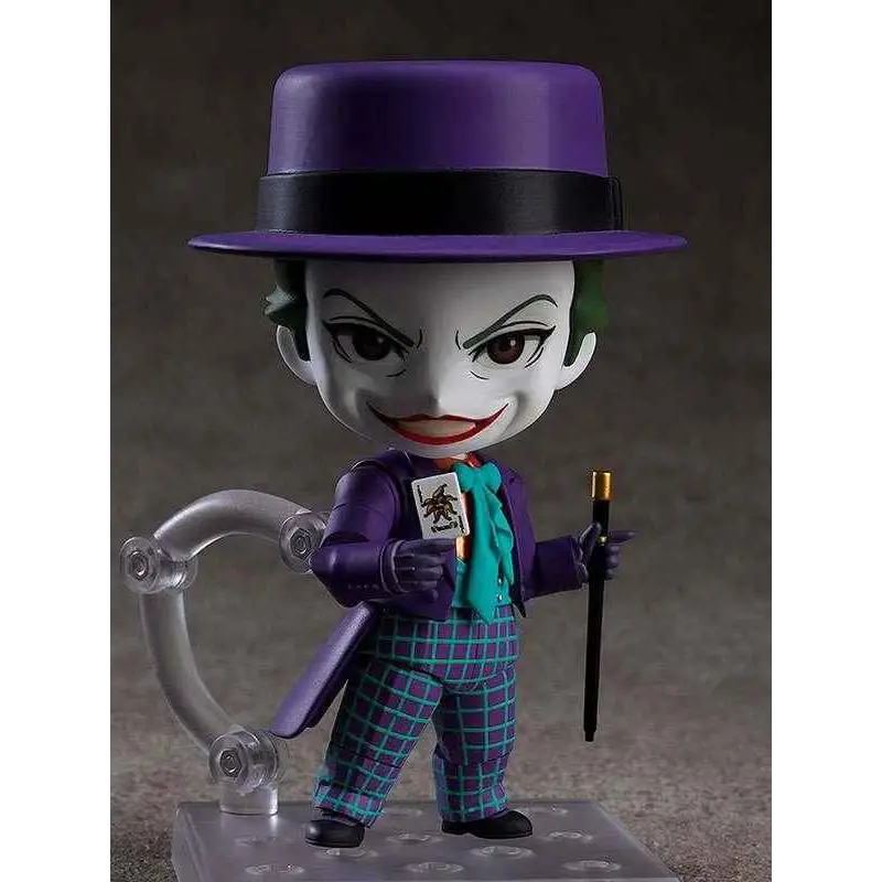 Lila-hattad Joker-figur i lila kostym med turkos scarf och rutiga byxor, håller kort och käpp
