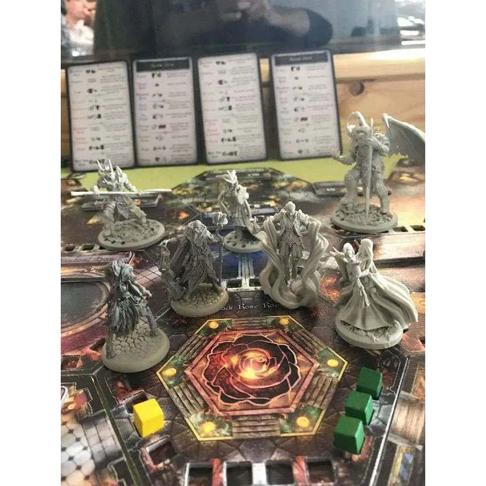 Grå resinminiatyrer av fantasykaraktärer på spelbräde med ornamenterad hexagon i Black Rose War - Fransk Utgåva