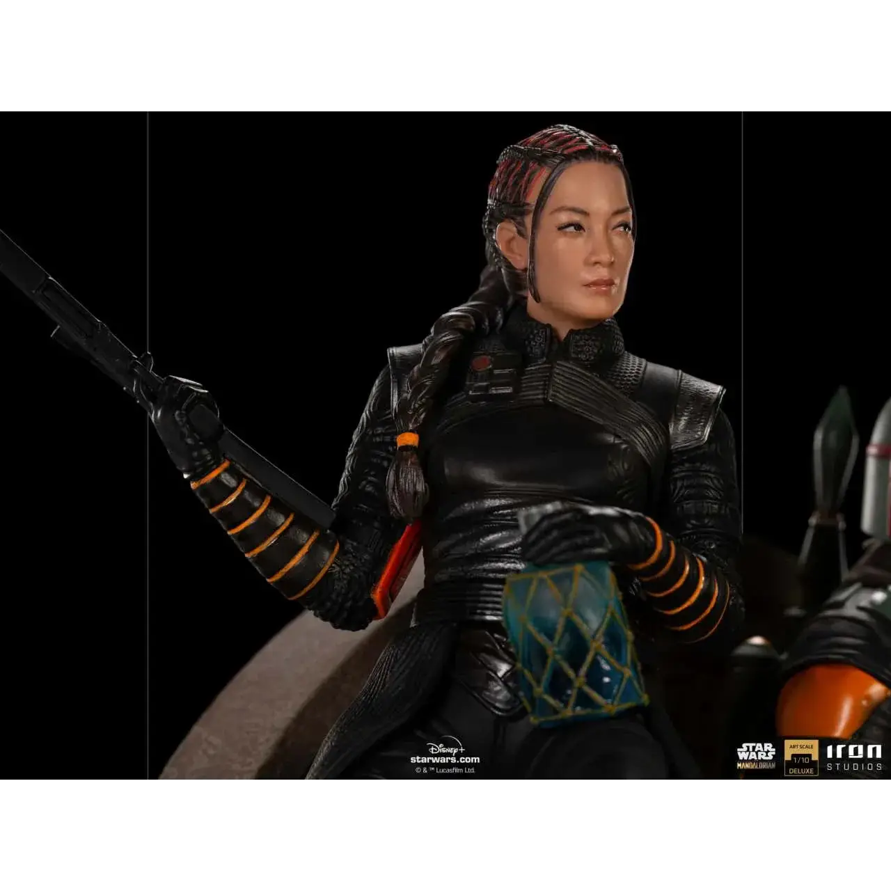 Svart rustad figur med flätat hår och orange accenter, håller blastergevär i Boba Fett och Fennec Shand deluxe 1/10 staty