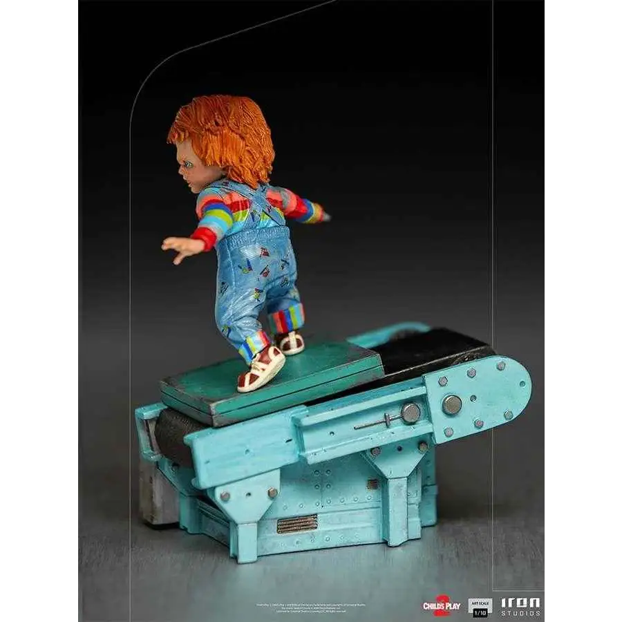 Chucky-statyett från Child’s Play II i regnbågsrandig tröja och blå overaller på turkos transportband