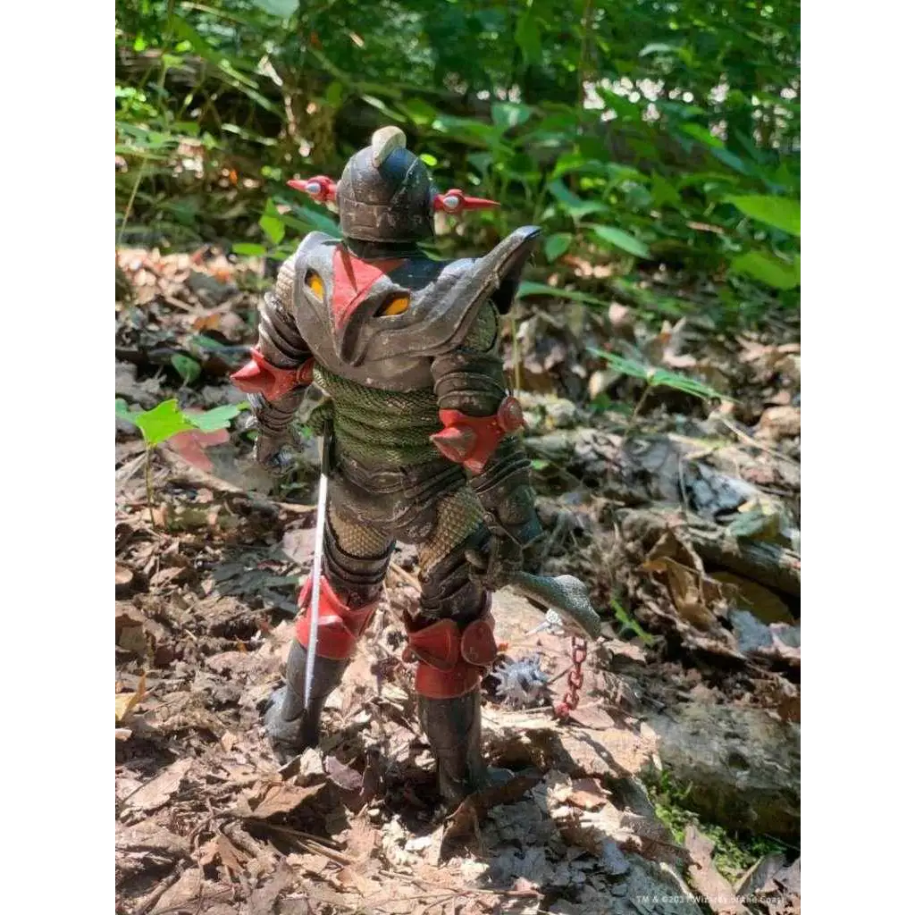 D&D Ultimate Grimsword actionfigur i svart och röd rustning med gula ögonaccenter på lövig mark