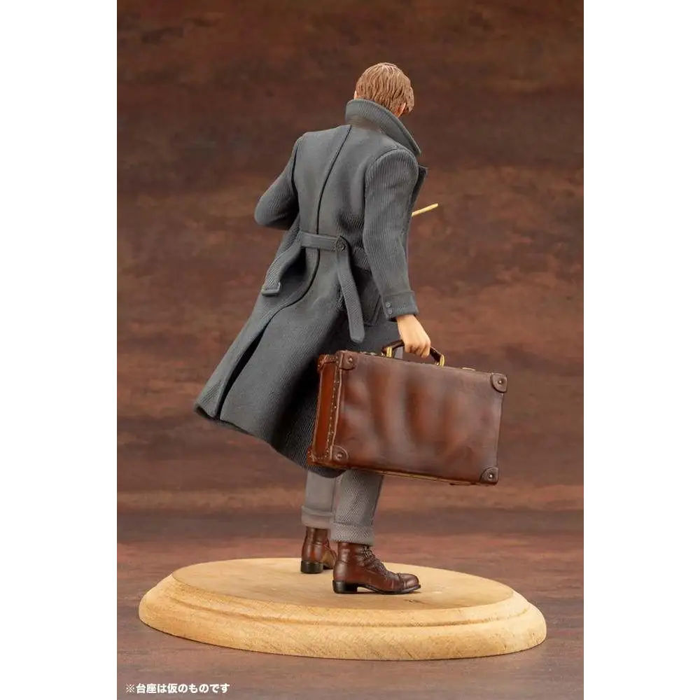 Grindelwald i grå mantel med bälte bär Newt Scamanders läderväska