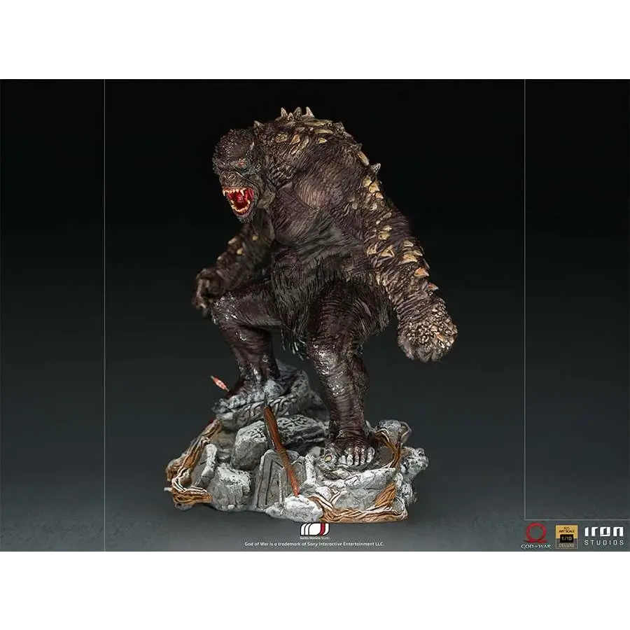 Mörk, texturerad Godzilla-staty med taggig rygg och röd mun på stenbas