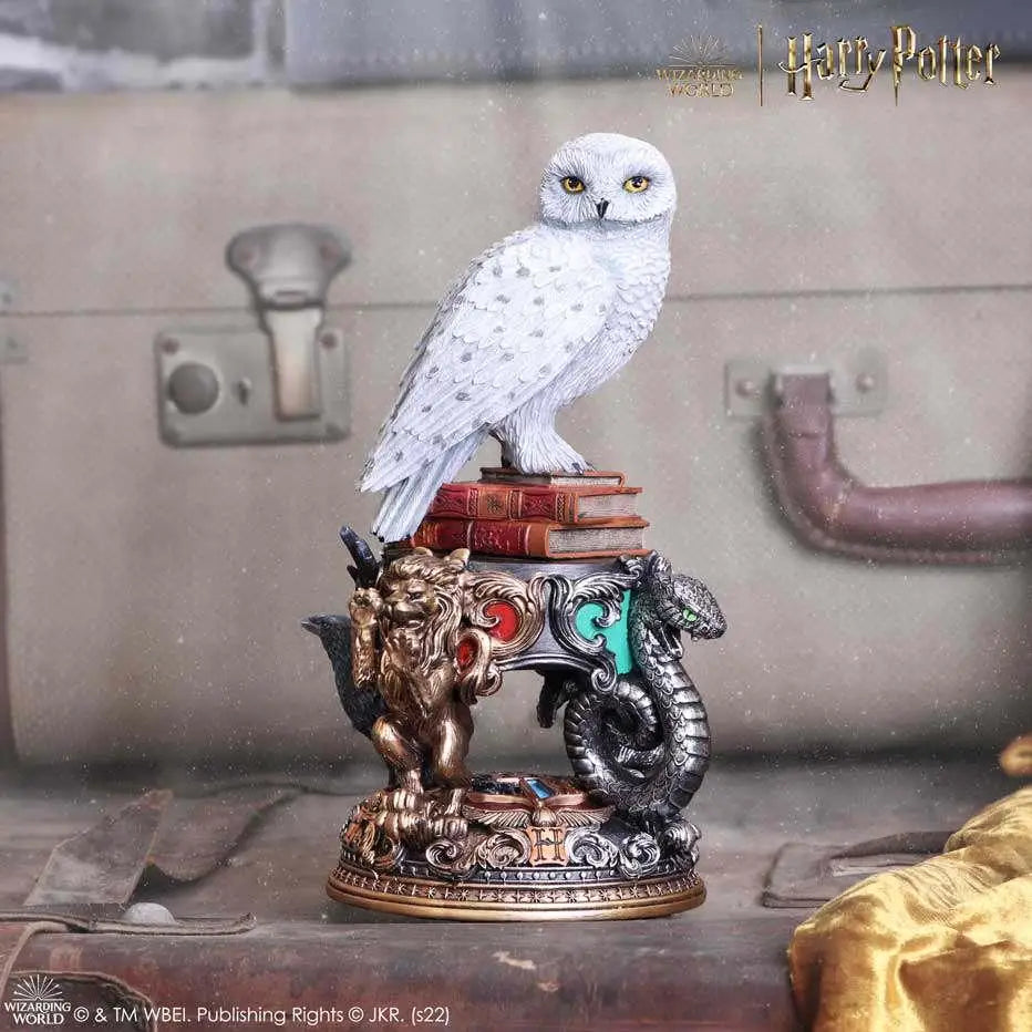 Vit snöugglafigur av Hedwig från Harry Potter på röda böcker med gyllene lejon och silverorm