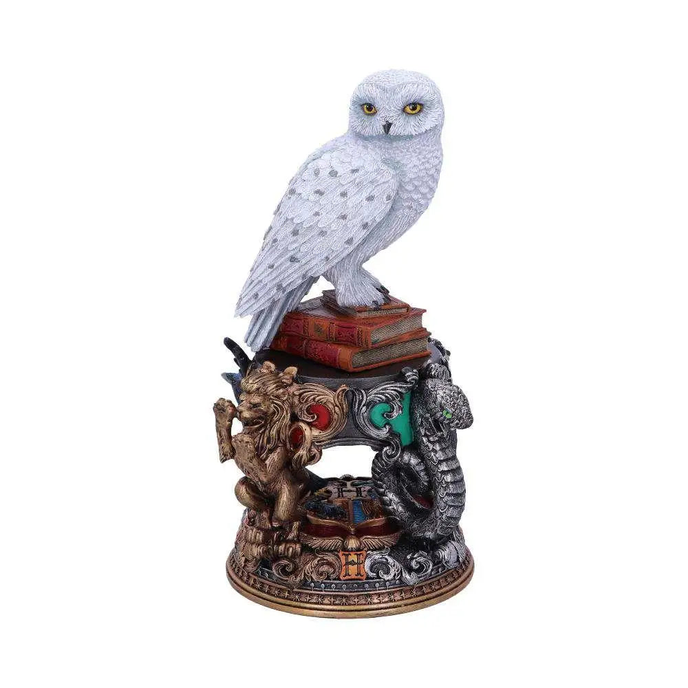 Vit Hedwig snöuggla statyett från Harry Potter på böcker med lejon- och ormdekor
