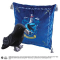 Plush svart korp med vit näbb och grå fötter framför blå Ravenclaw-kudde