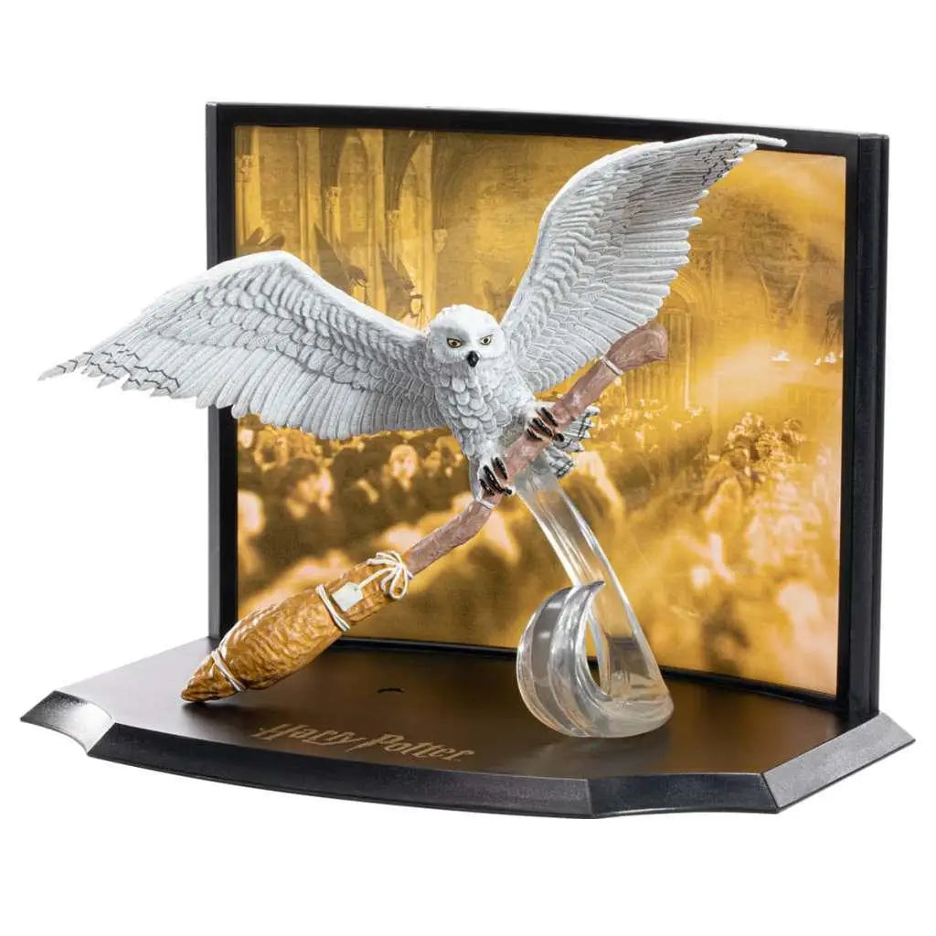 Vit snöugglafigur på gul trollstav i Harry Potter-diorama med Nimbus 2000