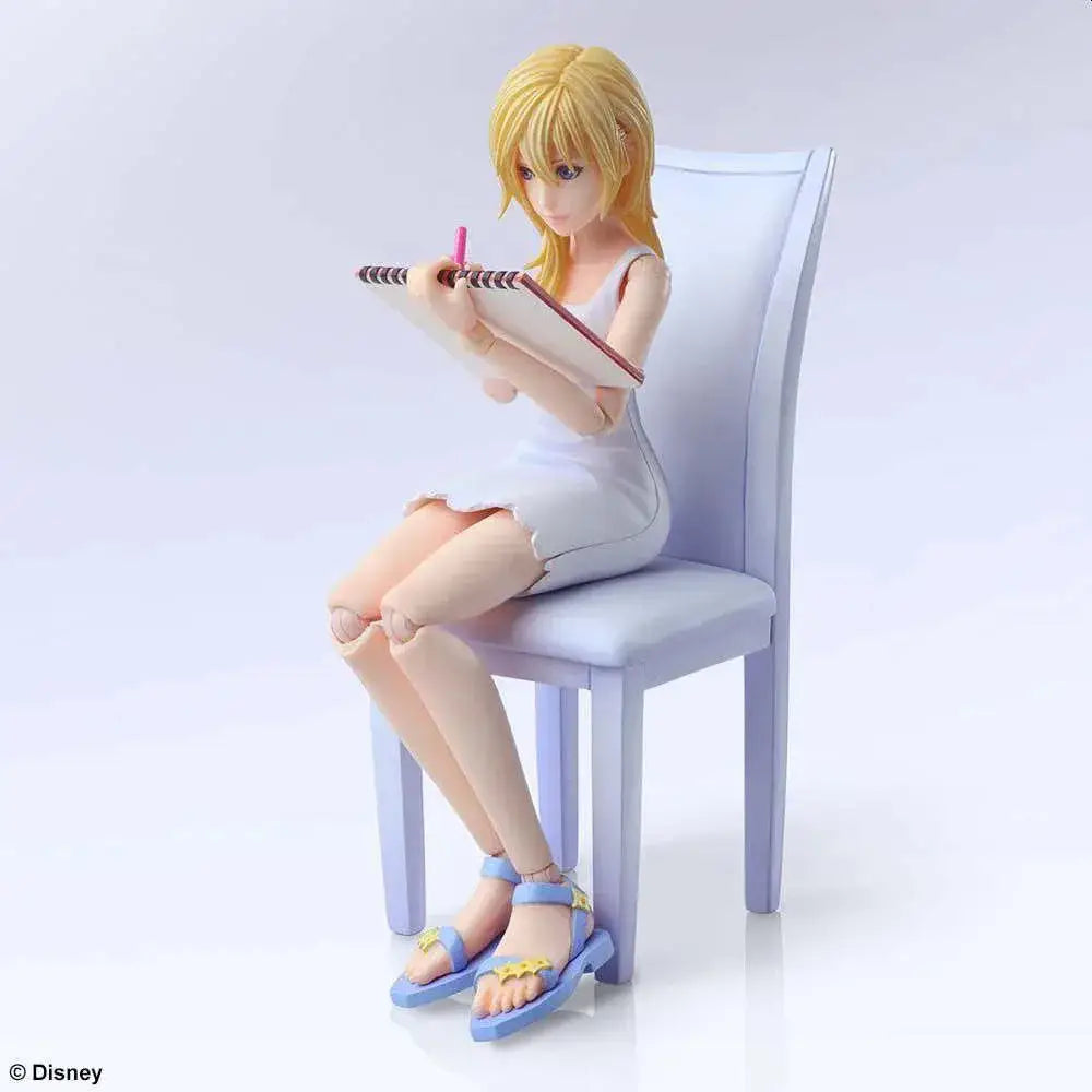 Naminé från Kingdom Hearts III, blond animefigur i vit klänning på lila stol med anteckningsbok
