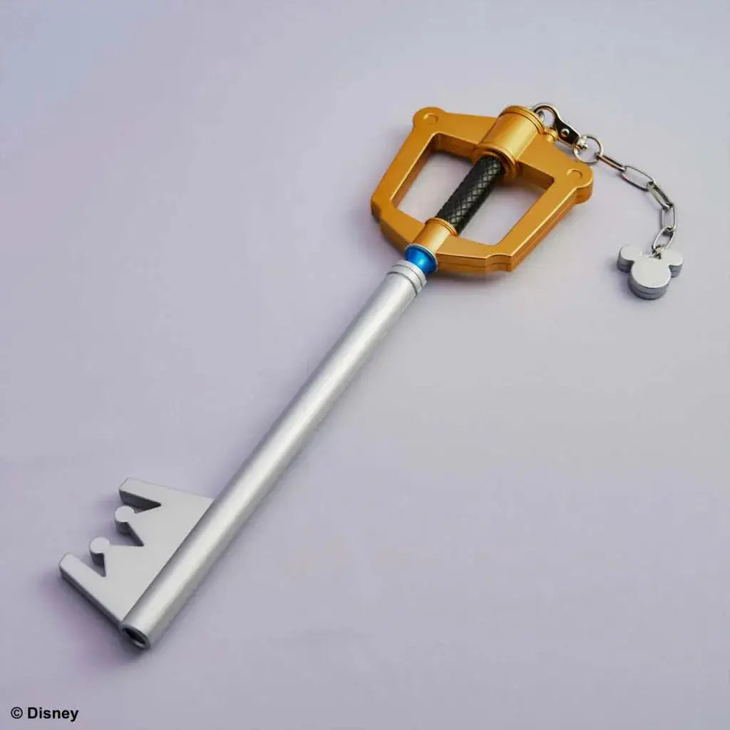 Guld- och silverfärgad Kingdom Hearts Ljusupplysande Keyblade-nyckelring med svart grepp, blå ring och Mickey Mouse-charm