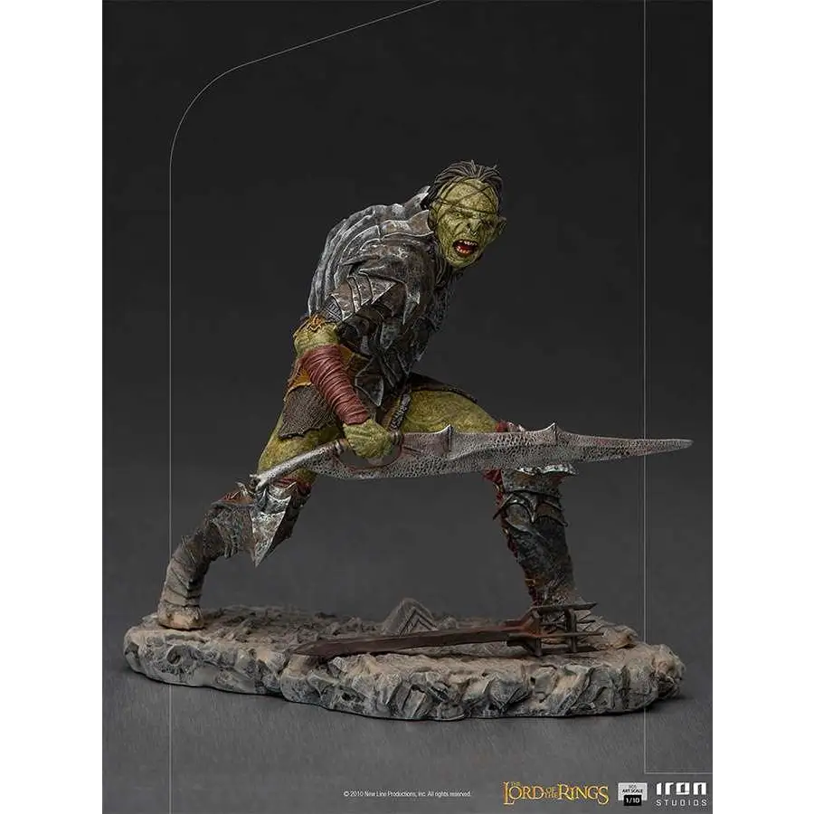 Grönskinnad orkkrigare i detaljerad metallrustning med rödinsvepta lemmar, svärd på stenbas från Lord of the Rings Orc Swordsman 1/10-statyett