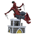 Röd och svart Daredevil-actionfigur i dynamisk pose med tvilling-sai på stenig skorsten