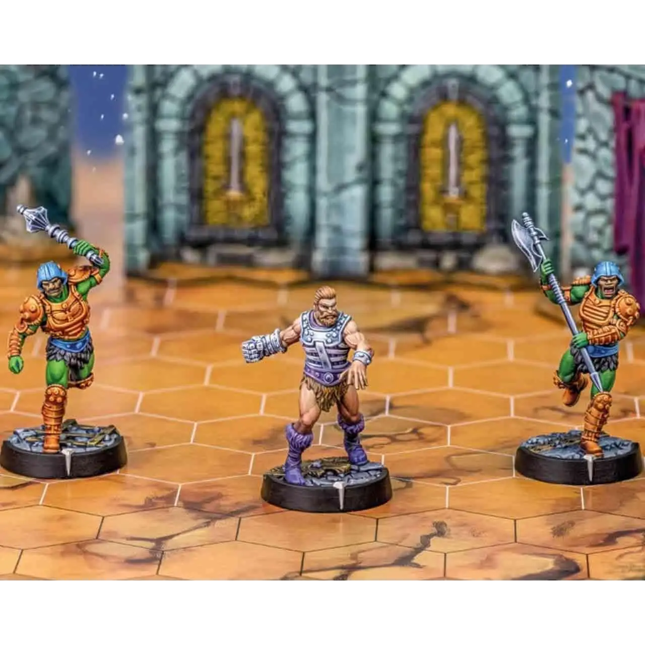 Tre detaljerade miniatyrfigurer från Masters of the Universe: Battleground - Wave 5 - Faction Edition, med rustning och vapen i gröna, orangea, lila och blåa färger
