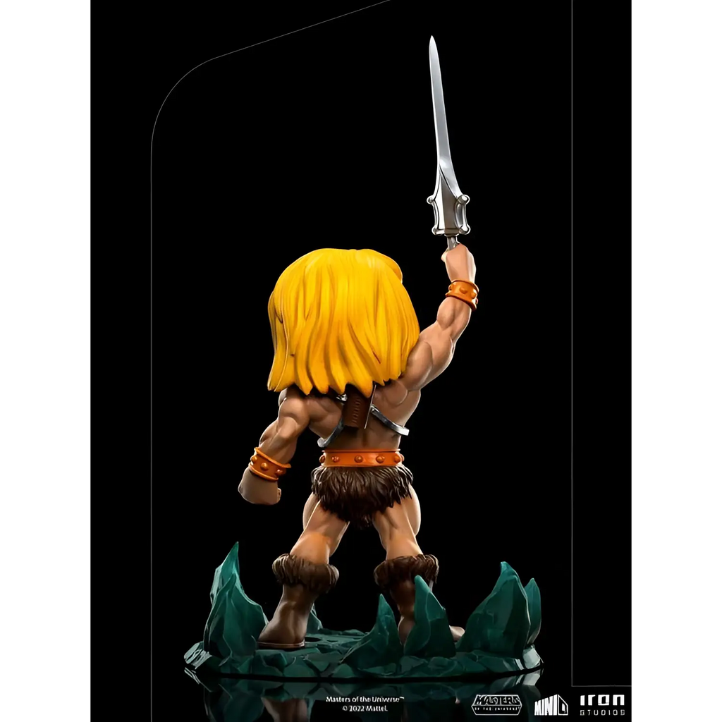 Chibi He-Man med guldigt hår, höjt svärd, orange bälte och brun pälsklädsel