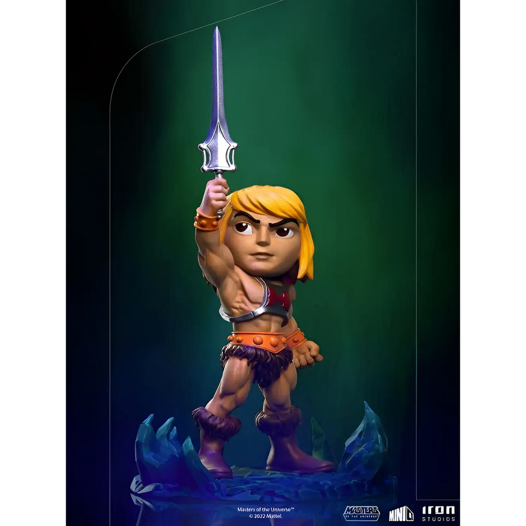 Chibi He-Man figurin med blont hår, muskulös byggnad, orange bälte och silver svärd på blå kristallbas