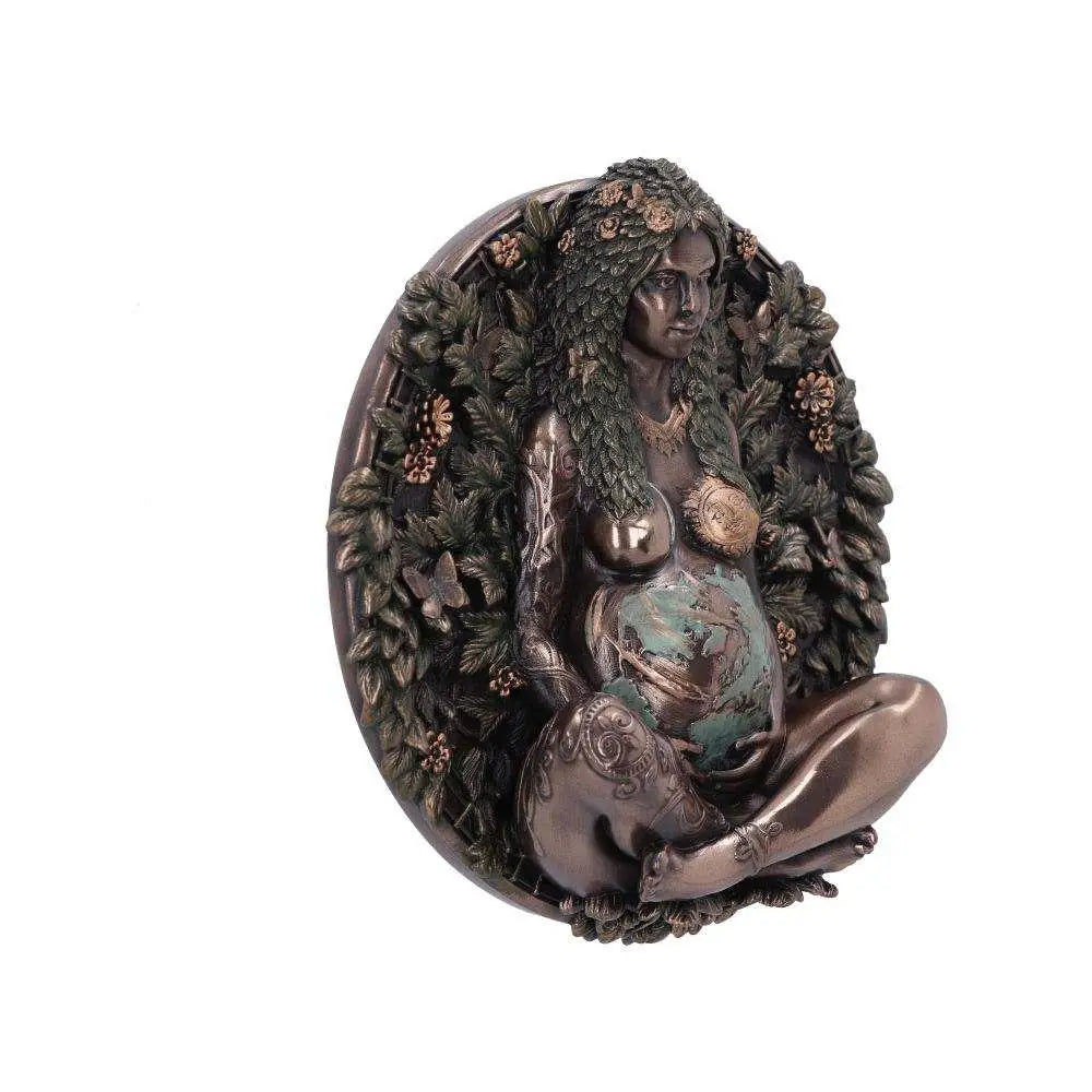 Bronsfärgad figur av gravid kvinna med lövigt hår och blomkrona i oval ram med grönska