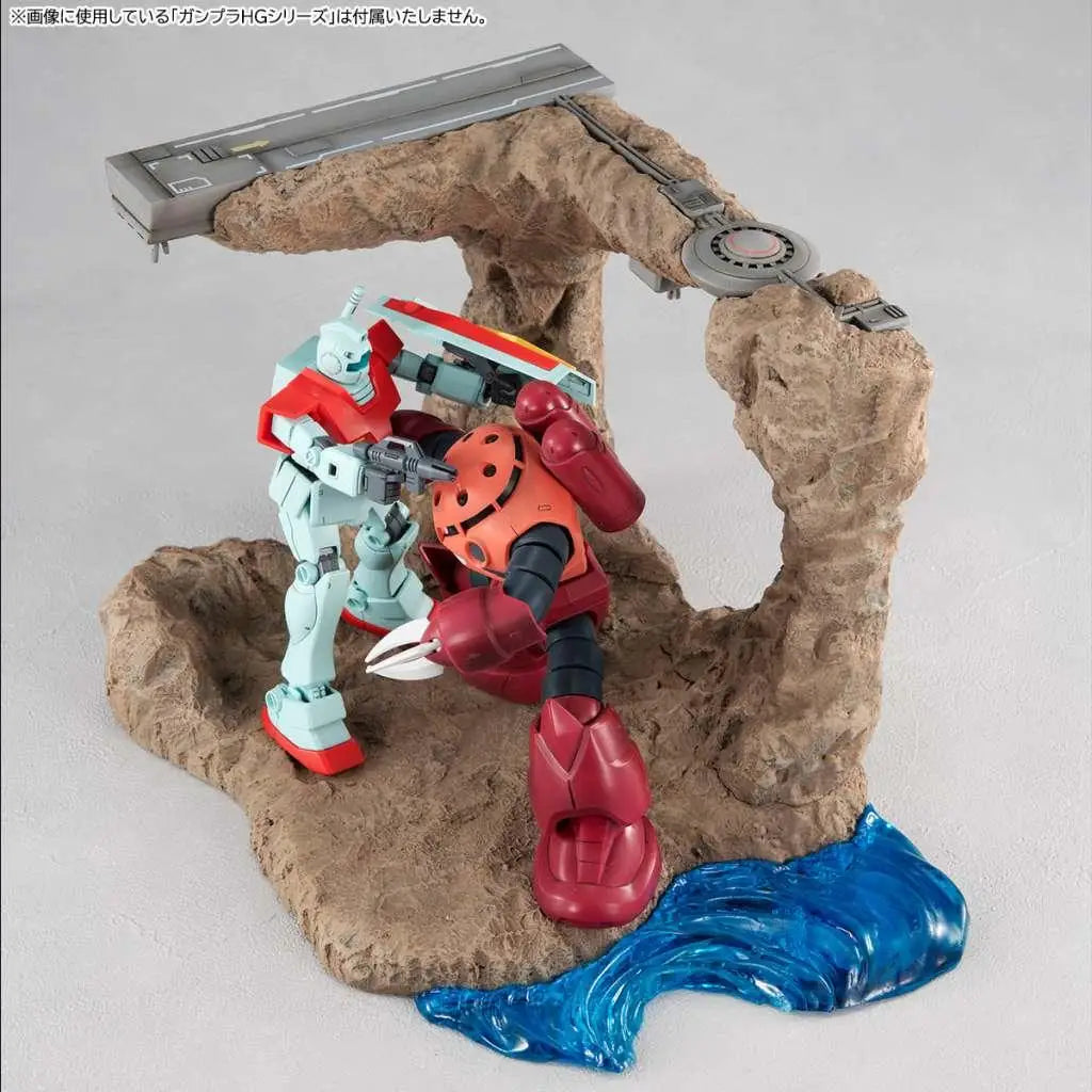 Röda och ljusblå Gundam-modeller i strid på öken-diorama med blå resin-vatten