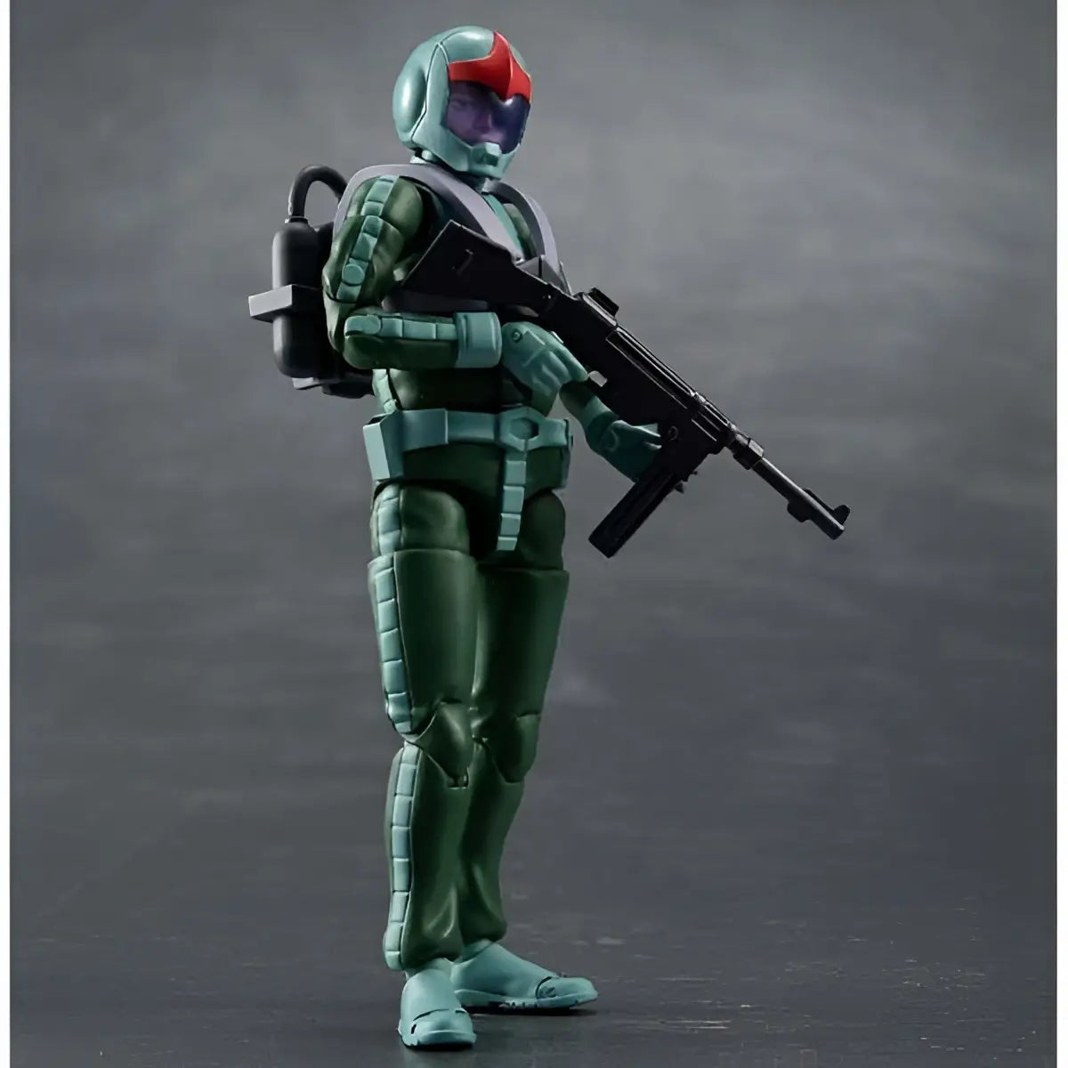 Grön och röd hjälmd Ms Gundam Zeon-soldat i Norm Suit med gevär