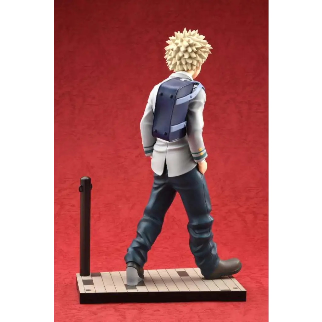 Detaljerad figur av spikig-håriga Katsuki Bakugo i ljusgrå kostym och mörkblå byxor med marin ryggsäck