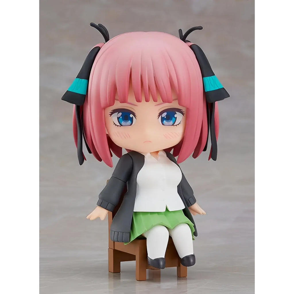 Rosa hårig animeflicka Nendoroid Quintessen Nino Swacchao! figurin med blå ögon i svart jacka, vit skjorta och grön kjol på trästol
