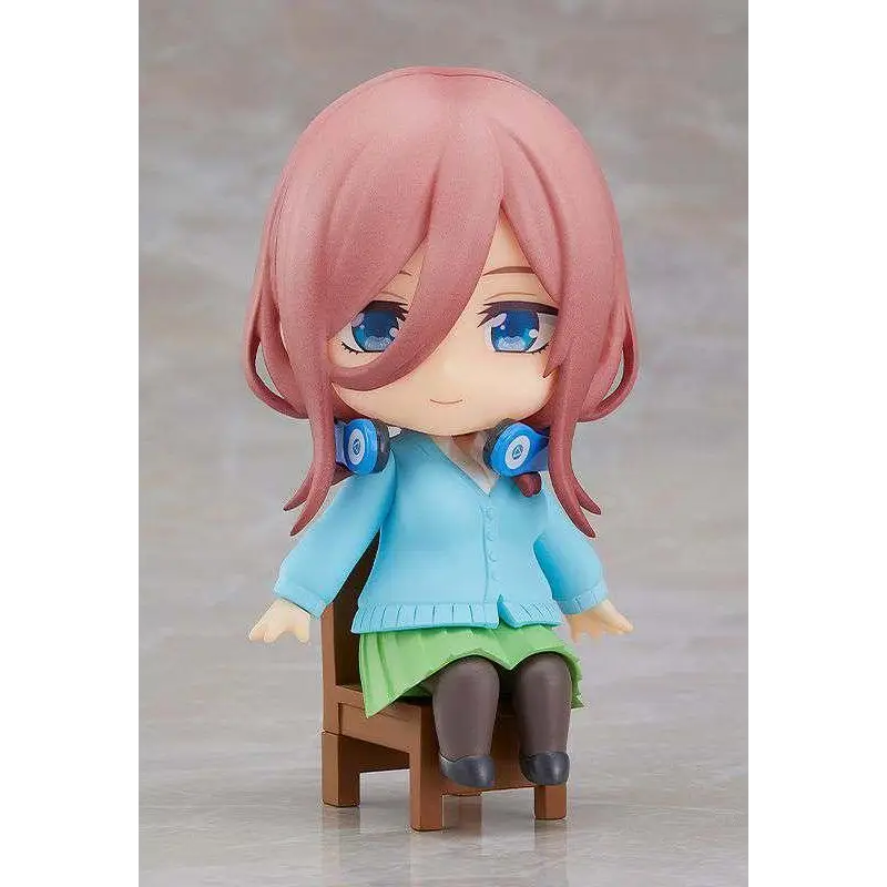 Rosa hårig animeflicka-figur Quintessen Quint Miku Nendoroid Swacchao med blå ögon, ljusblå kofta, grön kjol, sittande på trästol med hörlurar runt halsen