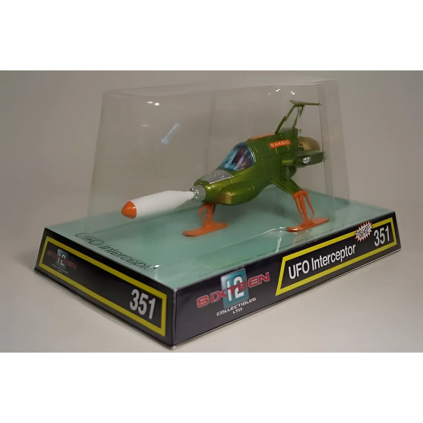 Retro UFO Interceptor diecast: grön och guld plast UFO-jaktplan med orange landningsställ i klar display