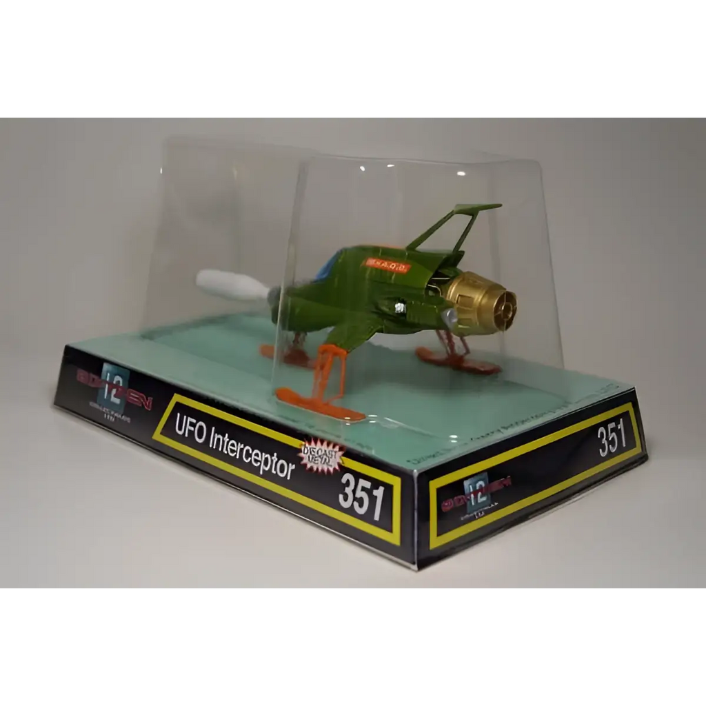 Retro UFO Interceptor Diecast: grön plastmodell med guldfärgad motor och orange landningsställ i klar skyddsbox på förpackning