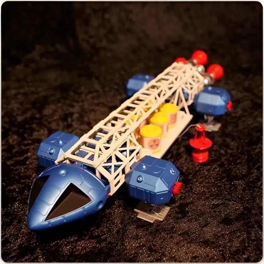 Blå plastleksakraket med vit gallerstruktur och röda, gula, blå cylindriska tillbehör, Space 1999 Retro Eagle Freighter-replika