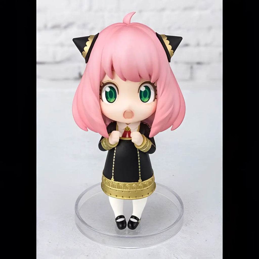 Rosa håruppfig chibi-figur av Anya Forger från Spy x Family, med gröna ögon och svart-guld outfit på klar plastbas