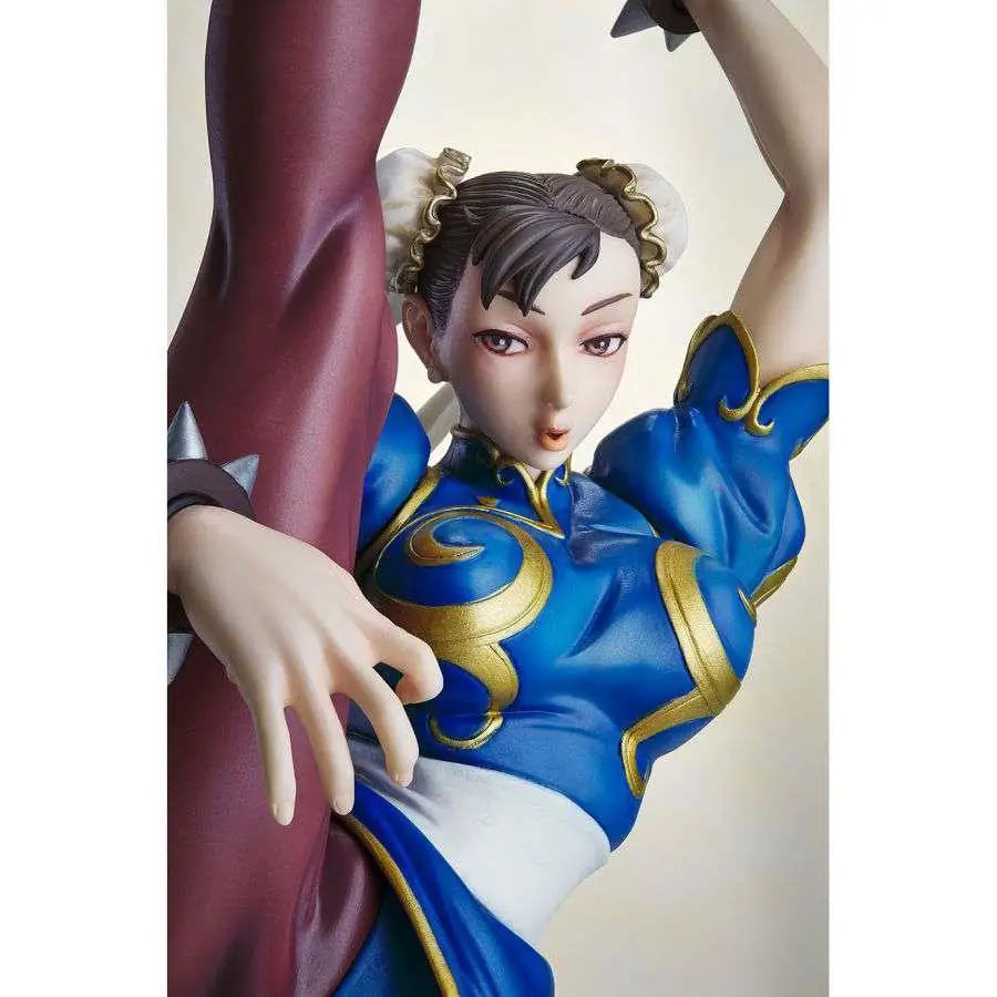 Detaljerad blå och guldfärgad Chun-Li-figur från Street Fighter i ikonisk pose med maroon cape