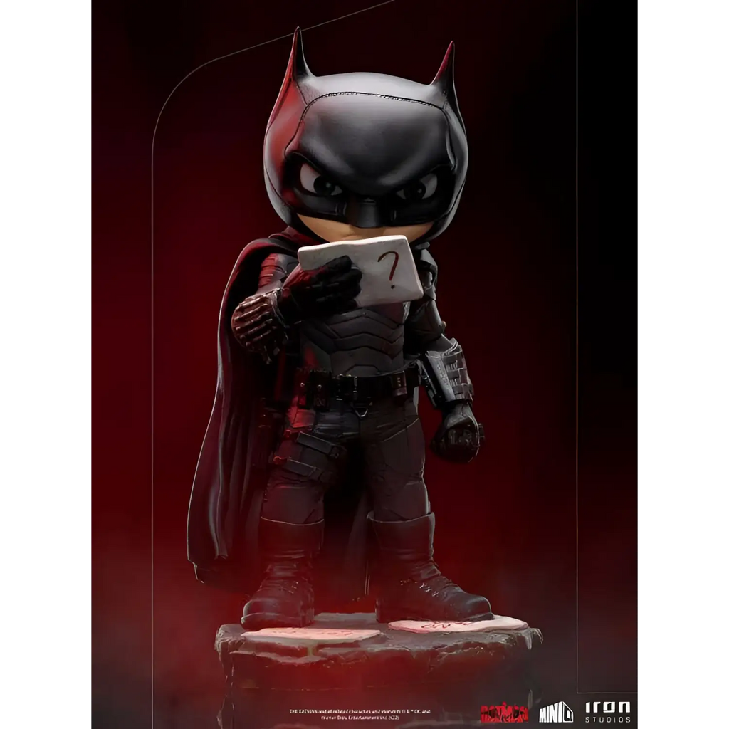 Chibi Batman-statyett i svart rustning med röda accenter, håller frågetecken-kort
