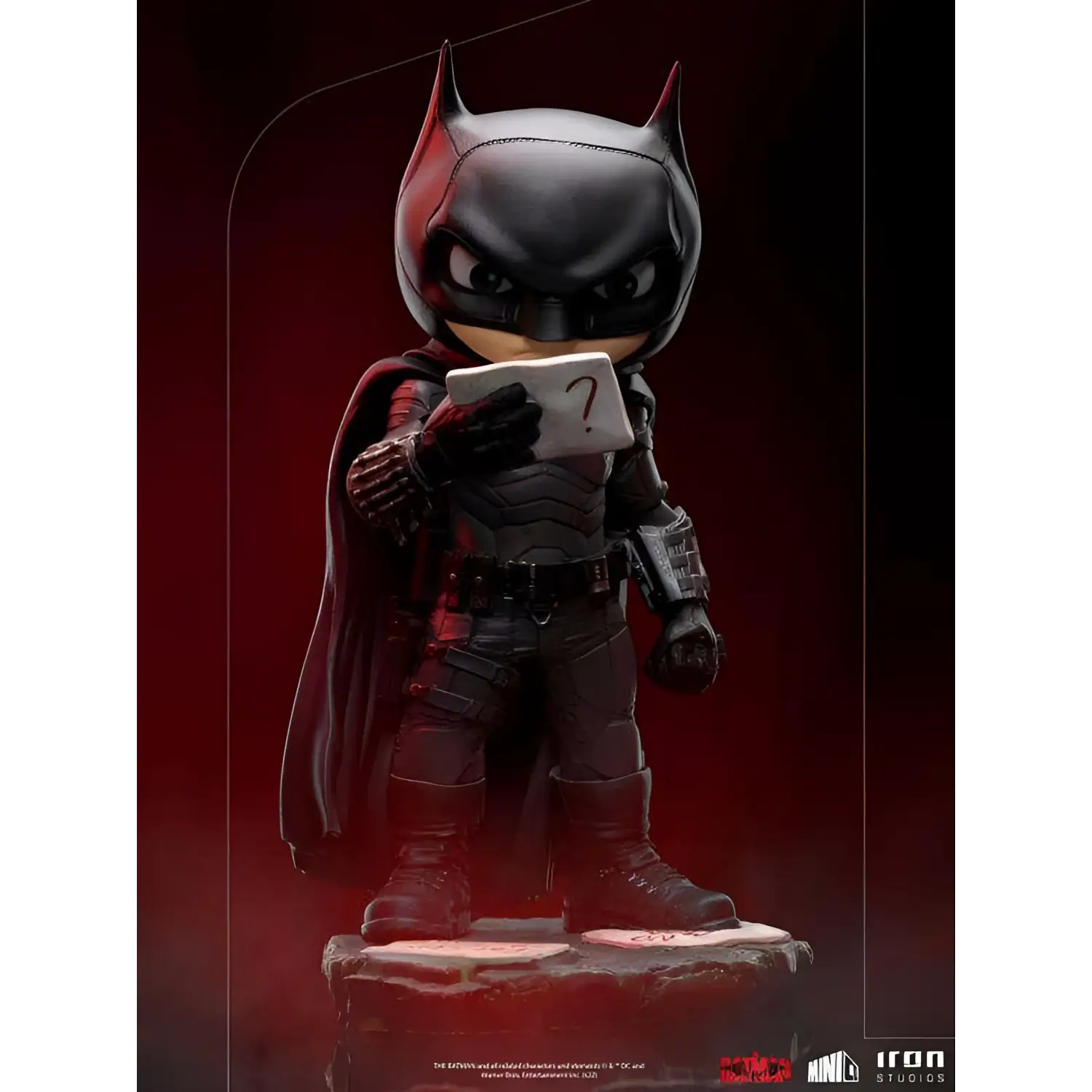 Chibi Batman-statyett i svart rustning med röda accenter, håller frågetecken-kort
