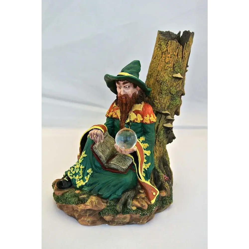 Grönklädd trollkarlsfigur med rött skägg på mossig stubbe med bok och kristallkula