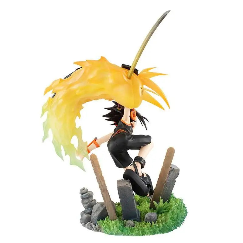 Yoh Asakura Shaman King-statyn med svart-orange figur, spikigt hår, svärd och gula flammor på gräsbas med gravstenar